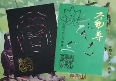 黒の切り絵は不動明王像のお顔、緑の切り絵には不動明王「カン」の梵字と制吒迦童子「タ」、矜羯羅童子「タラ」のお顔が切り抜かれております。
見開き御朱印を背景に、画像加工してみました。