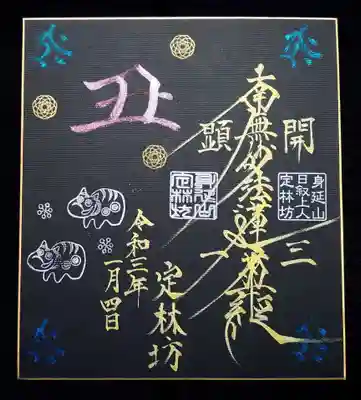 正月限定の御首題は「飾れるご首題」で、黒色紙に疫病退散のあかべこ、丑年の守護神の梵字、丑の字と、牛を牛牛(ぎゅうぎゅう)詰めにしたとのことです🐮
シックでありながら金文字のお題目、ピンクの丑の字の映える、素敵な御首題です。
まさに飾れる御首題。早速、部屋の壁に飾らぜて頂きました😄
